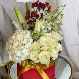 Medium square box floral arrangement with hydrangeas, roses, lilies, cabbage flowers, orchids and hypericum berries