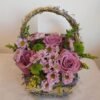 Small basket arrangement with five roses, green and purple chrysanthemums, and solid asters